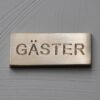 Skylt gäster mässing